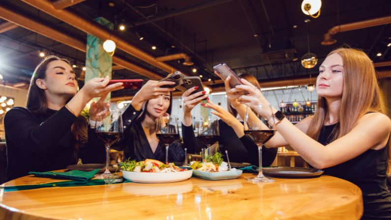 Group of women taking photo of food on the table using their phones.